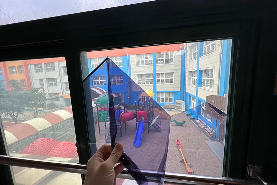 필름 샘플을 창문에 대보며 색감과 밝기를 비교하는 모습